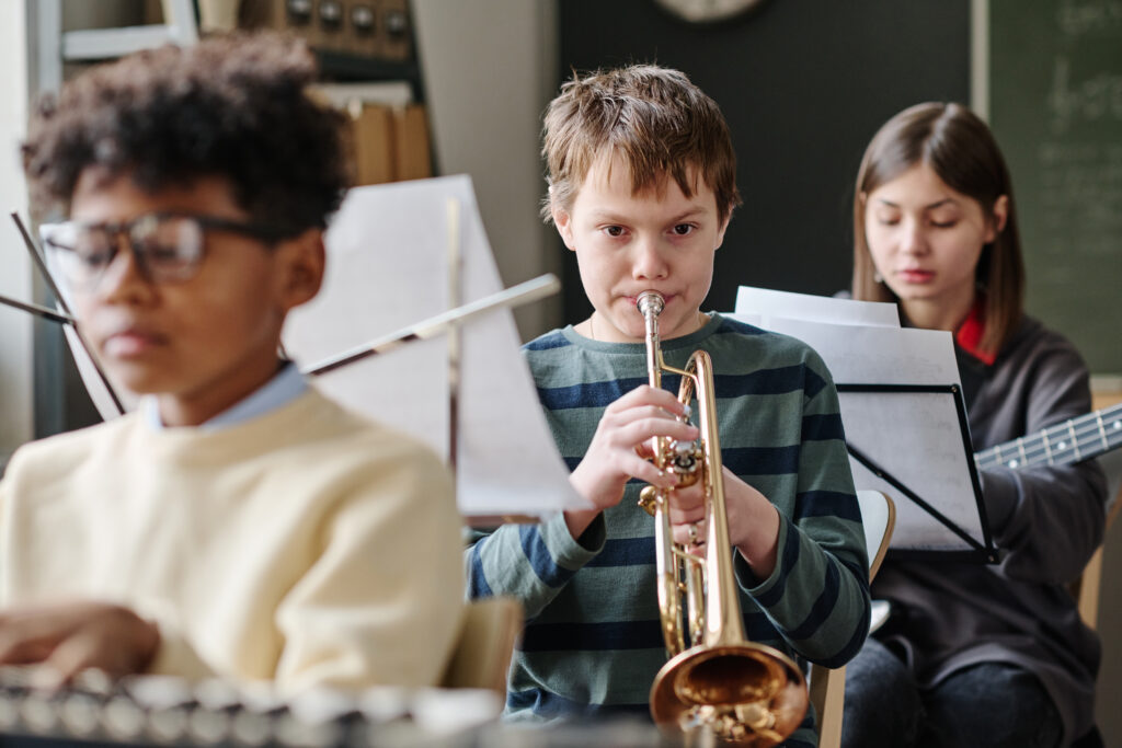 boy playing trumpet in orchestra at school